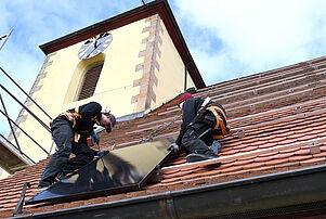 Handwerker montieren Solarpanele auf das Dach der Salvatorkirche in Ungstein. © Kretzschmar 